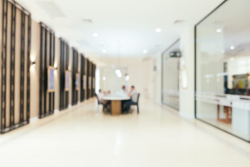 Espacio amplio de trabajo con personas al fondo ligeramente desenfocadas, que transmite colaboración y continuidad dentro de una estructura organizada.